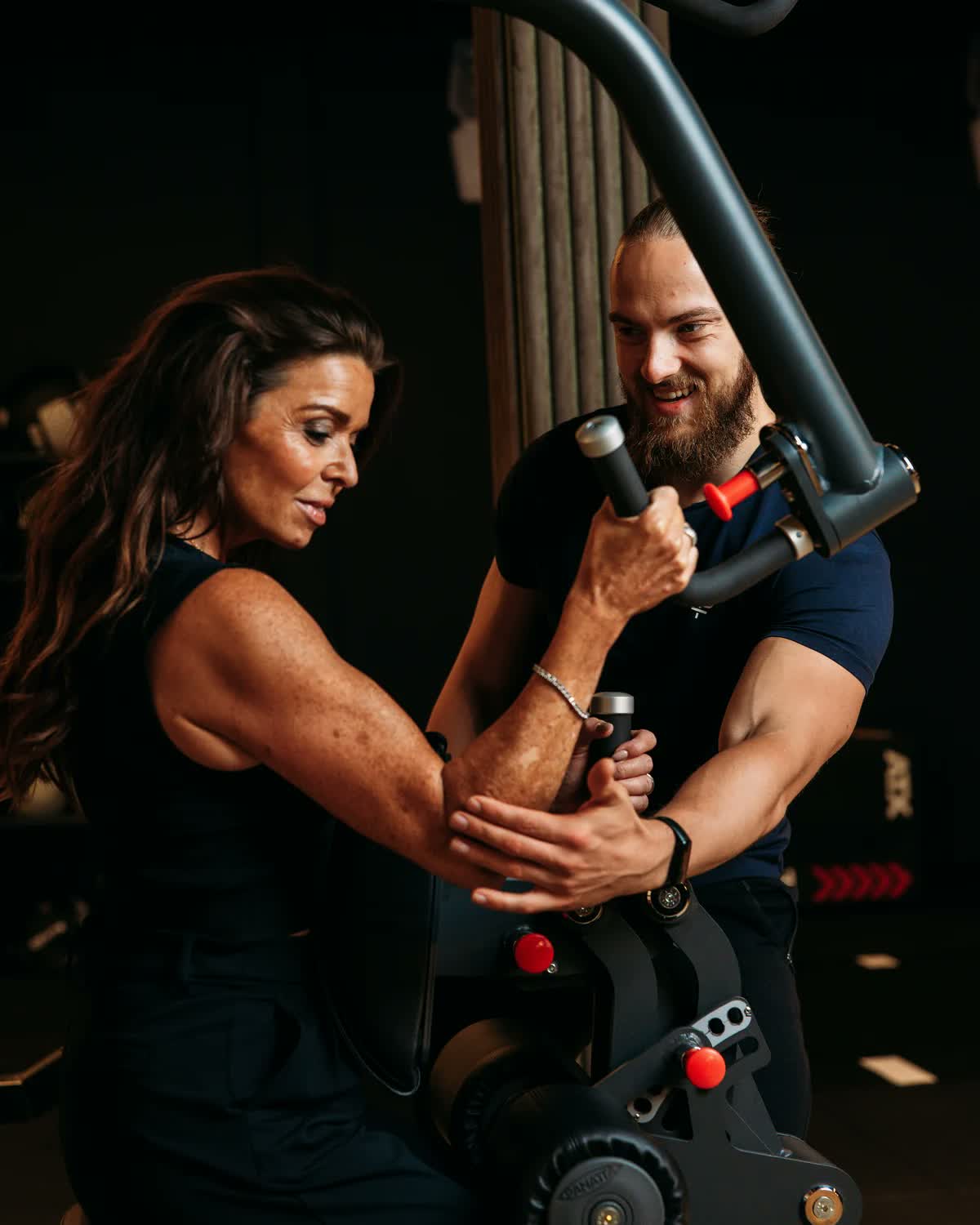 Een coach stuurt de armstand van een lid bij op een krachtmachine