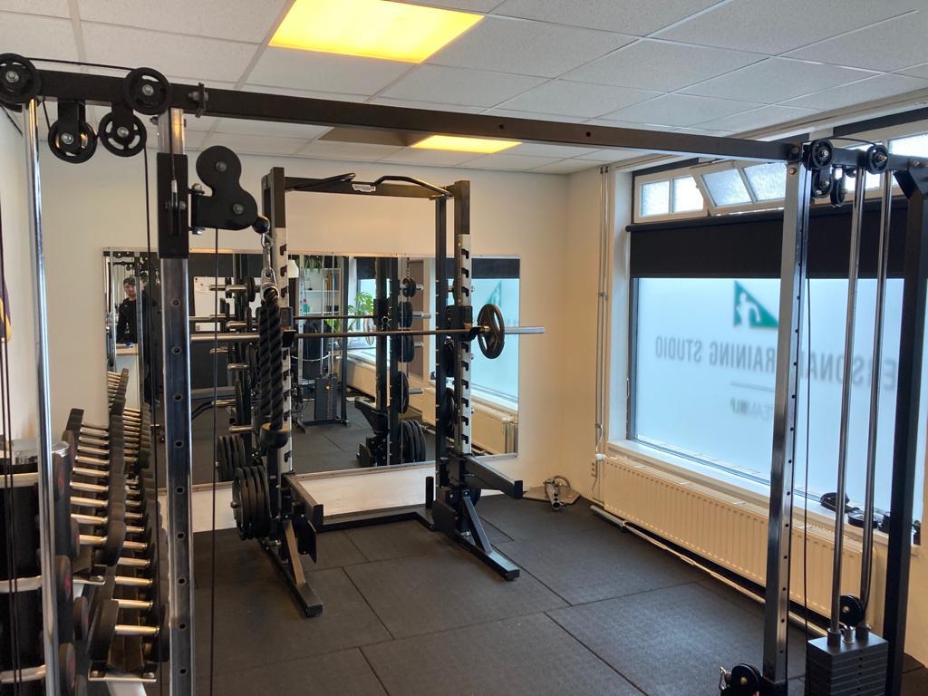De trainingsvloer van de eerste studio: een rek, een kabelstation en een spiegel